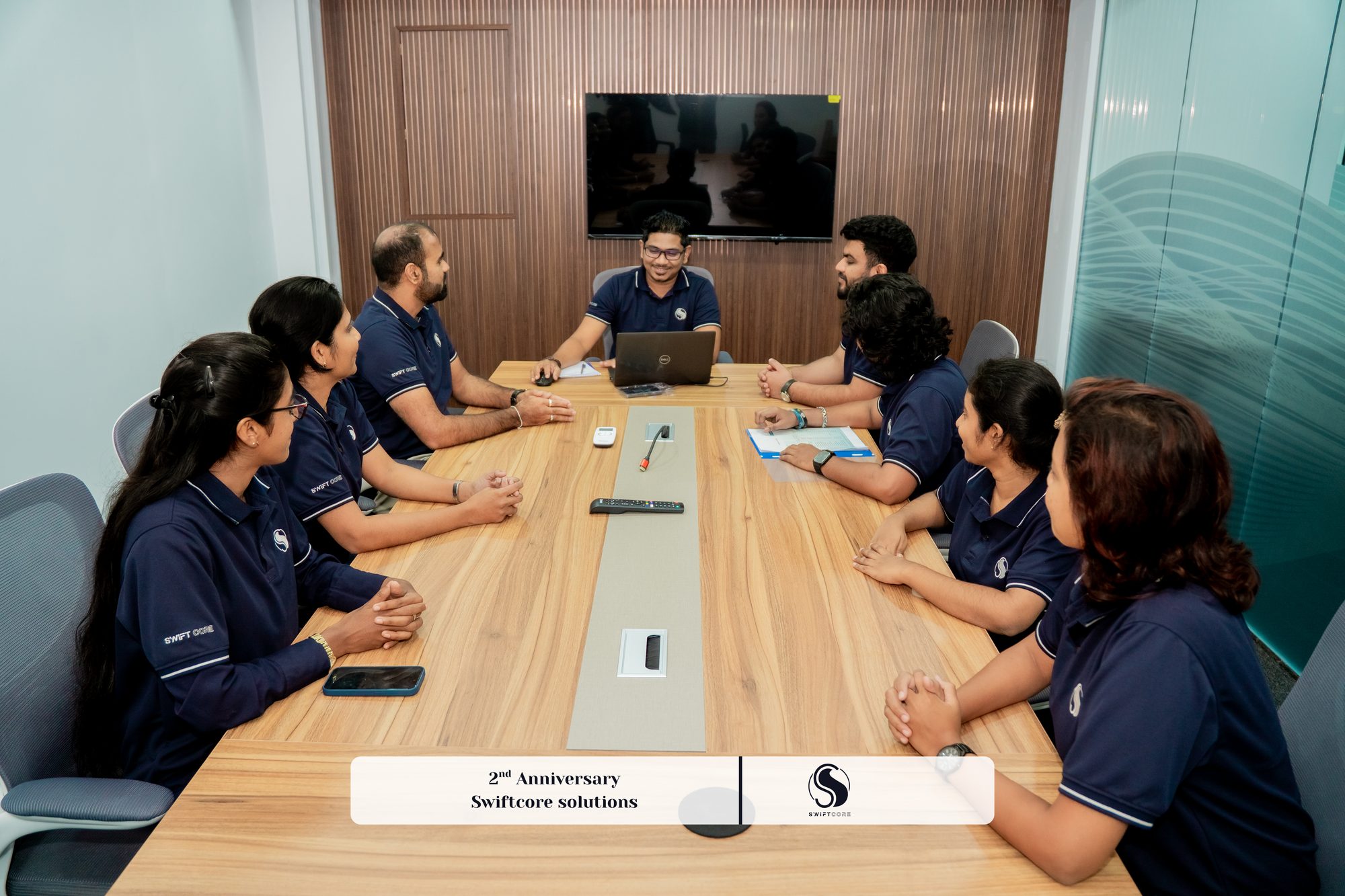 Swiftcore team members in navy company polos around a boardroom table in a meeting